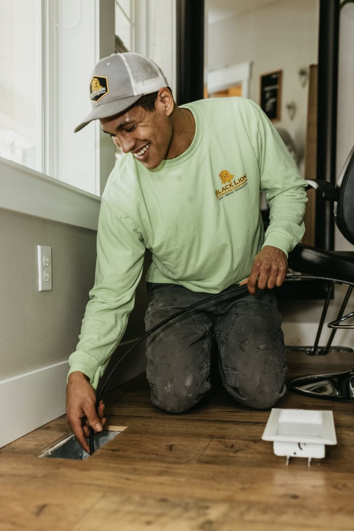 Black Lion HVAC technician checking inside of floor vent.