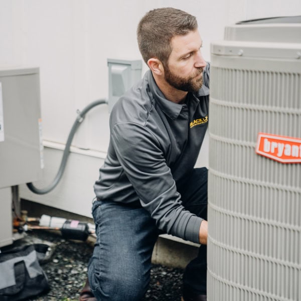 Black Lion HVAC technician working on outdoor heat pump equipment.