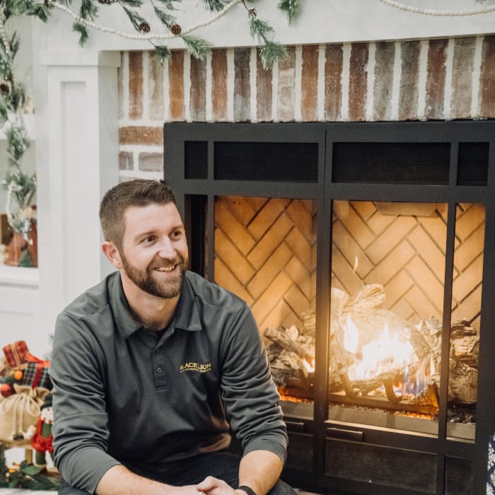Black Lion HVAC technician sitting in front of newly installed gas fireplace.