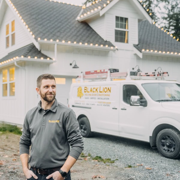 Black Lion HVAC technician standing in front on house with newly installed outdoor lighting.
