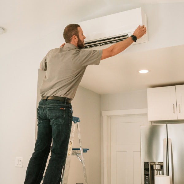 DSC01920 Black Lion HVAC technician on a ladder checking ceiling ductless system.