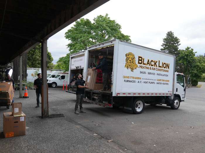 Black Lion HVAC technicians unloading equipment off of branded work truck.