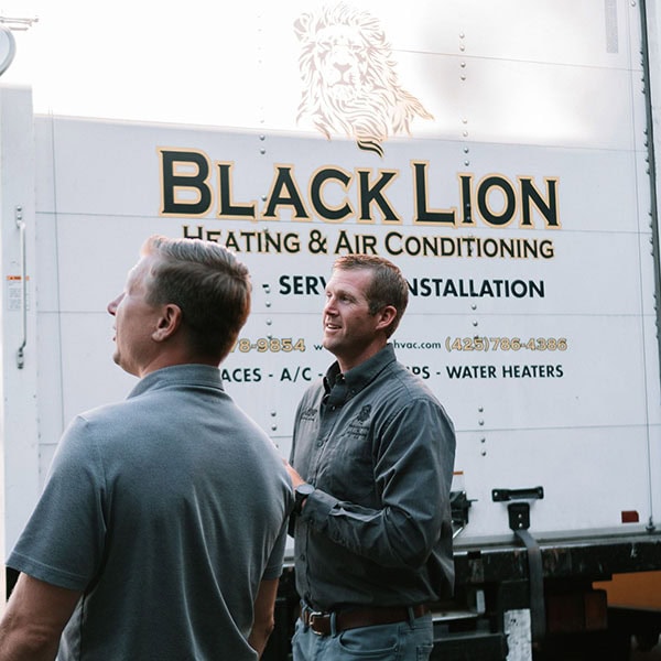 Black Lion HVAC technicians standing outside of company truck.