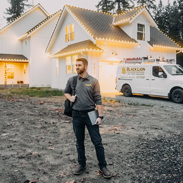 Black Lion HVAC technician standing outside of house.