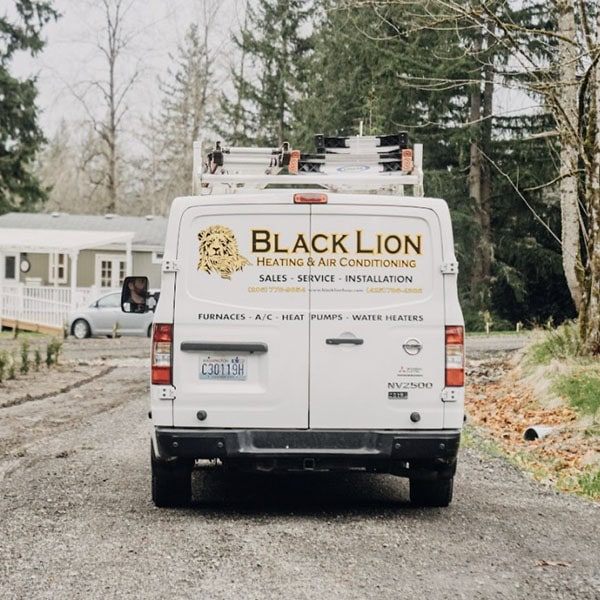 Black Lion Heating, Air Conditioning, & Electrical technician company truck driving to a house for an air conditioning repair.