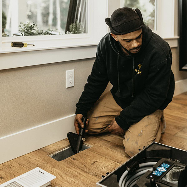 Black Lion Heating, Air Conditioning, & Electrical technician fixing an air duct.