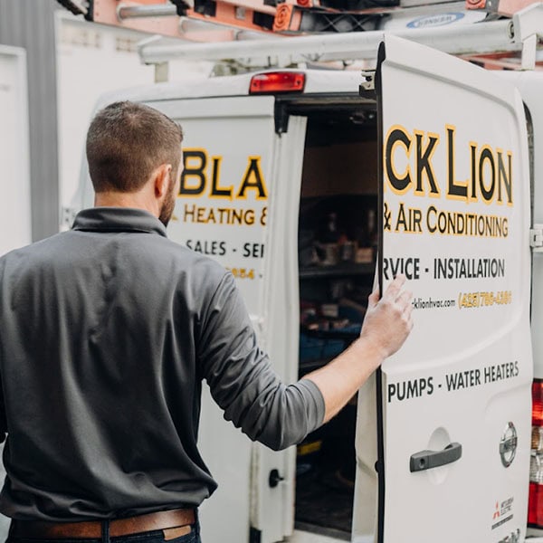 Black Lion Heating, Air Conditioning, & Electrical technician closing the back door of the company truck.