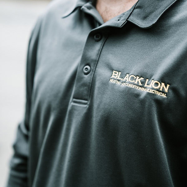 Close up of a Black Lion Heating, Air Conditioning, & Electrical technician shirt.