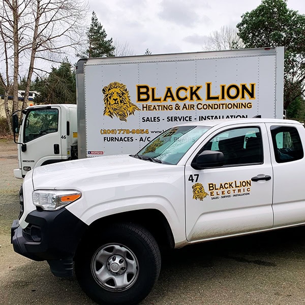 Two Black Lion Heating, Air Conditioning, & Electrical company trucks.
