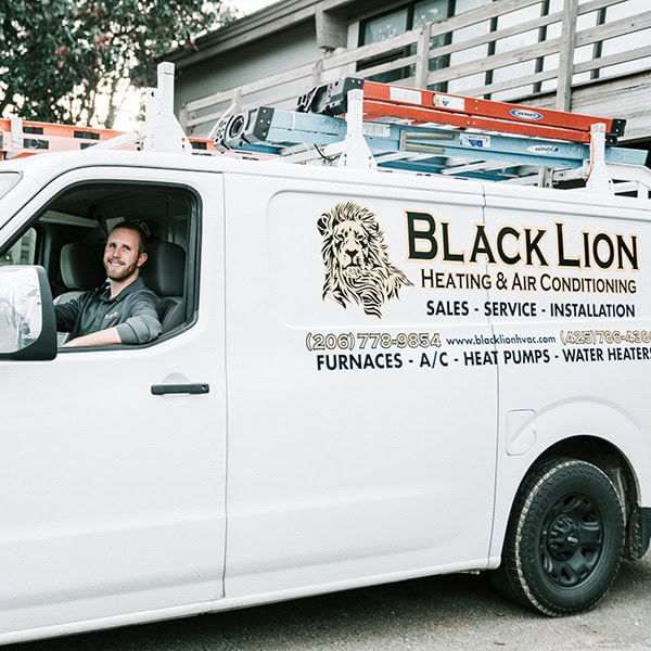 Black Lion Heating, Air Conditioning, & Electrical technician smiling while sitting in the company truck.
