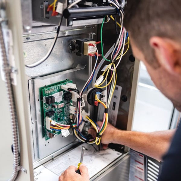 Black Lion Heating, Air Conditioning, & Electrical technician performing maintenance on a gas furnace.