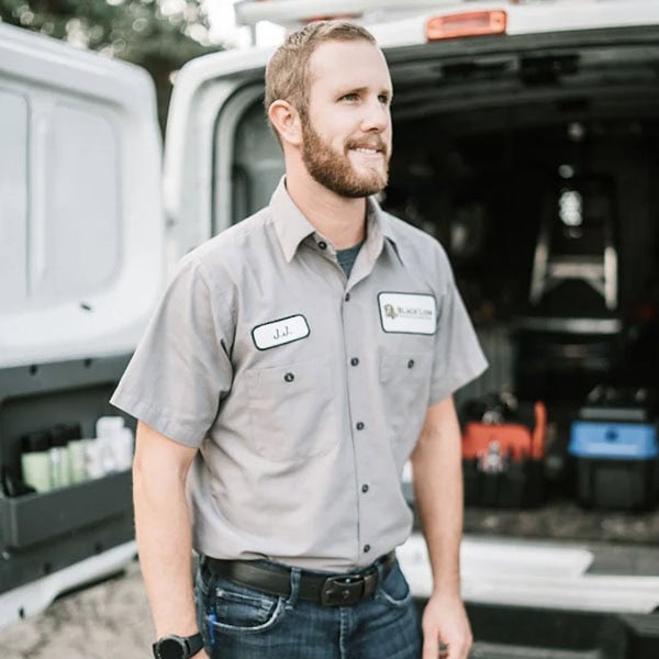 Black Lion Heating, Air Conditioning, & Electrical technician standing in front of the truck