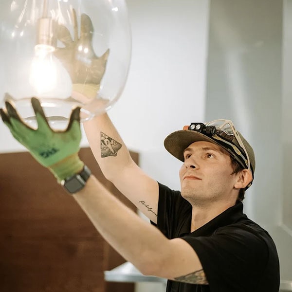 Black Lion Heating, Air Conditioning, & Electrical technician screwing in a light bulb.