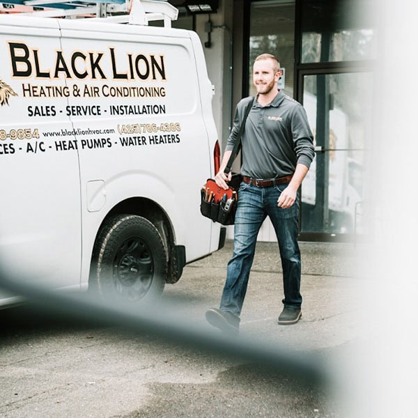 Black Lion Heating, Air Conditioning, & Electrical technician walking next to company truck.